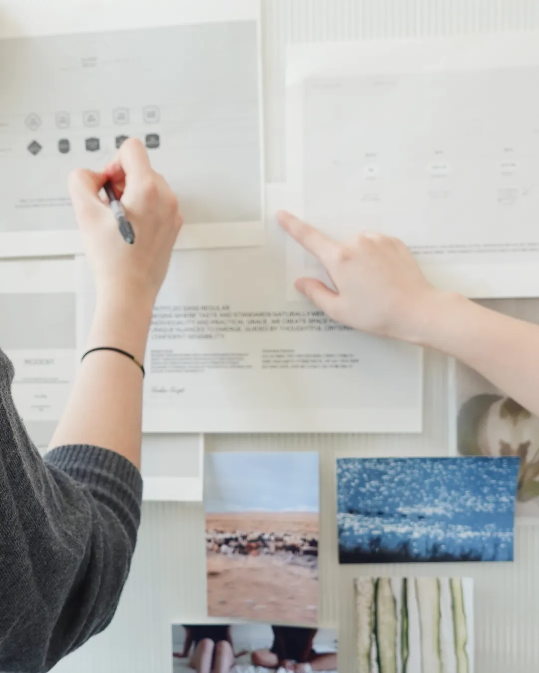 Hands reviewing printed brand layouts pinned to a studio wall